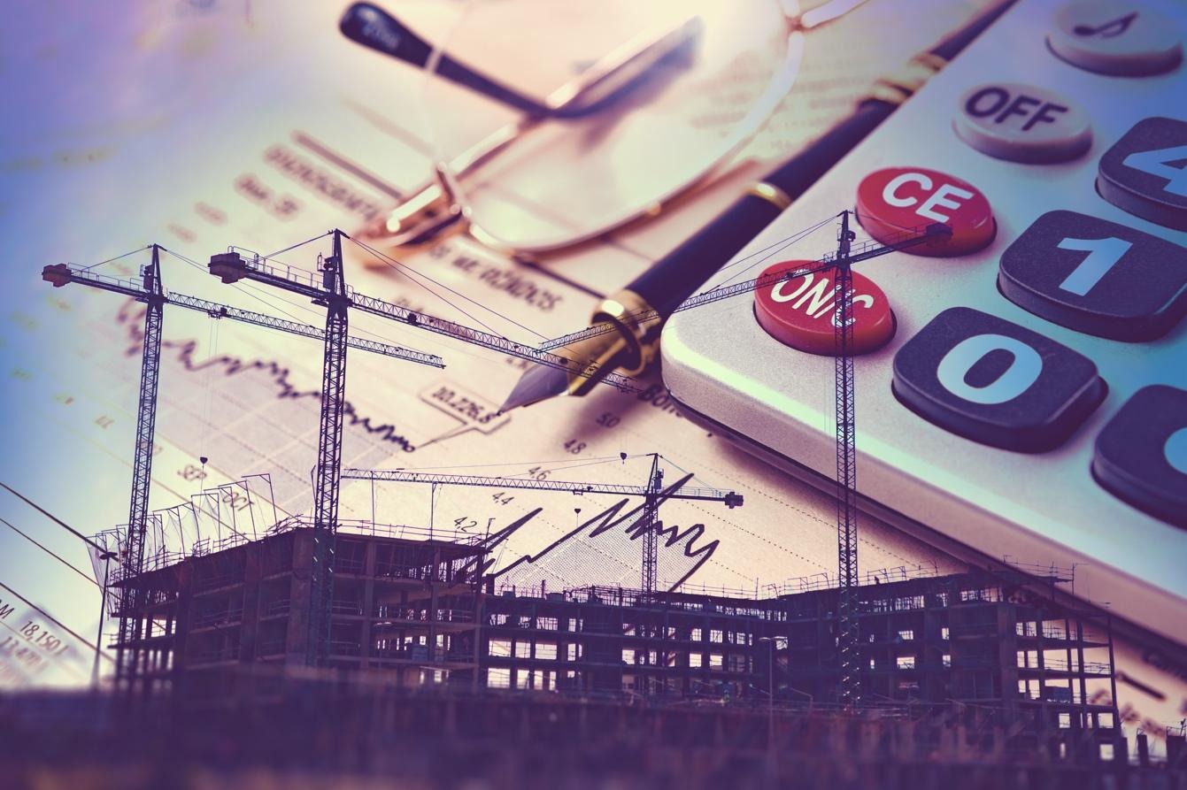 New construction in the foreground with calculator, pen, glasses and reports in the background