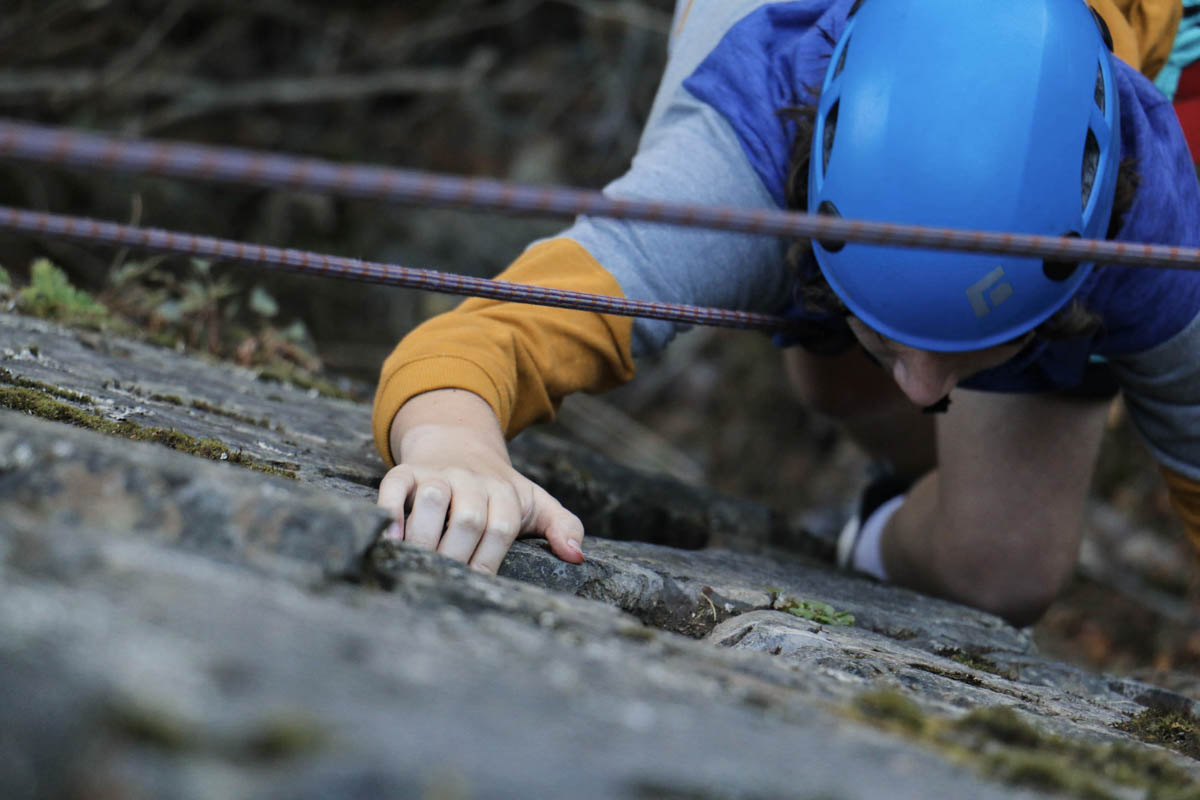 A close up of a campers hand grasping the rock as he ascends the climbing route.