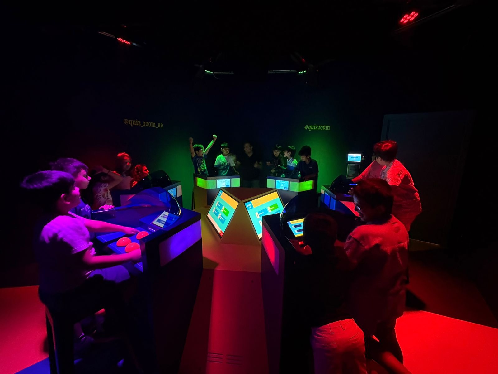 Children buzzing answers in a quiz game show setting