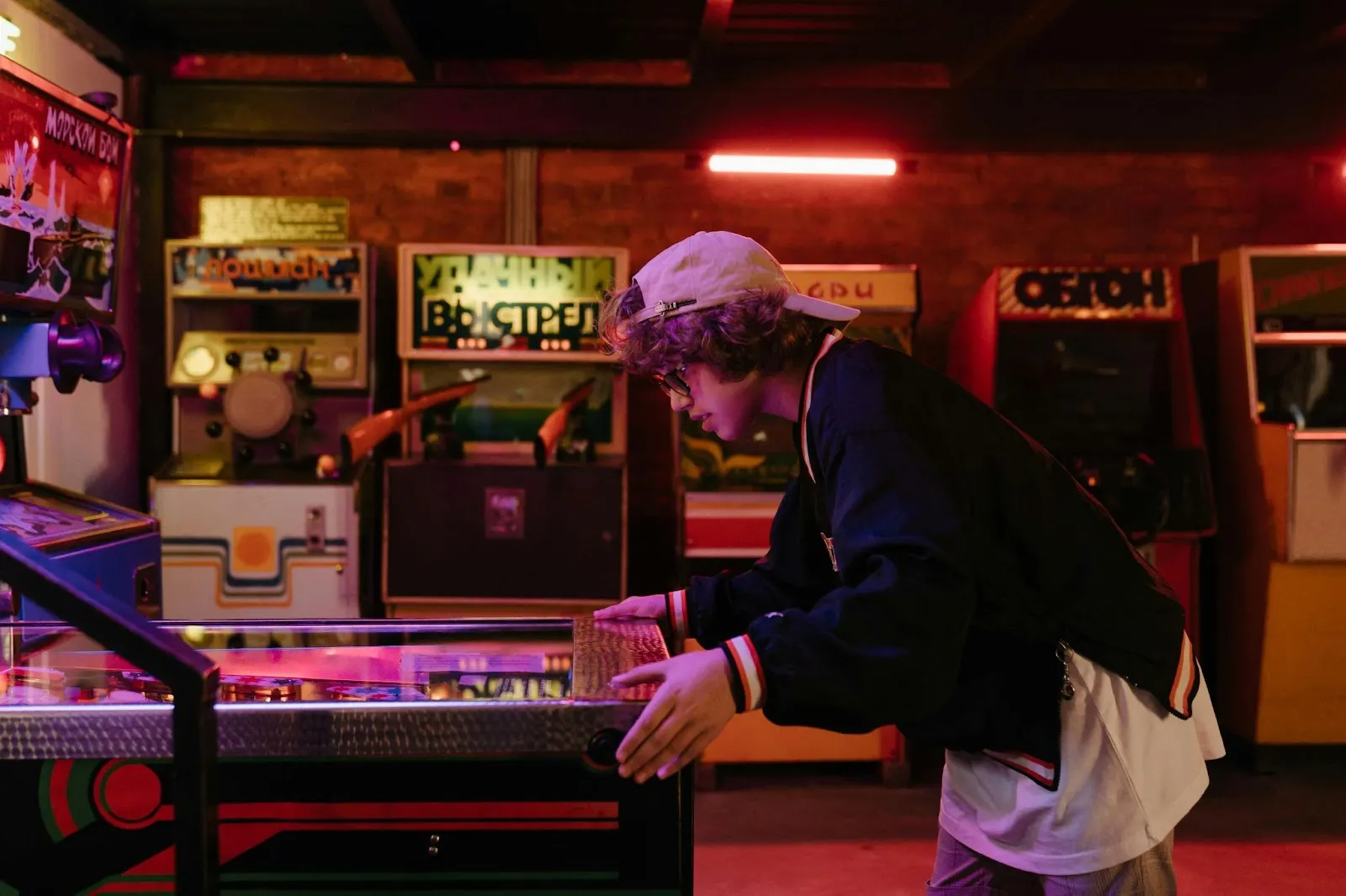 Group of friends playing arcade games in a neon-lit retro gaming café in Dubai