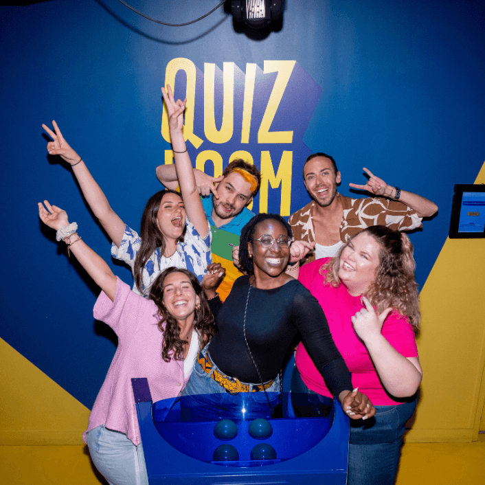 Group of young adults celebrating at Quiz Room Dubai, a fun team-based trivia game experience with bright colors and energetic vibes.