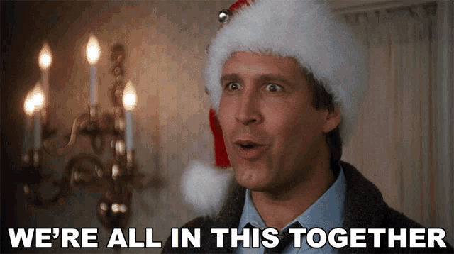 Clark Griswold wearing a Santa hat saying "We're all in this together" from the classic holiday movie National Lampoon’s Christmas Vacation.