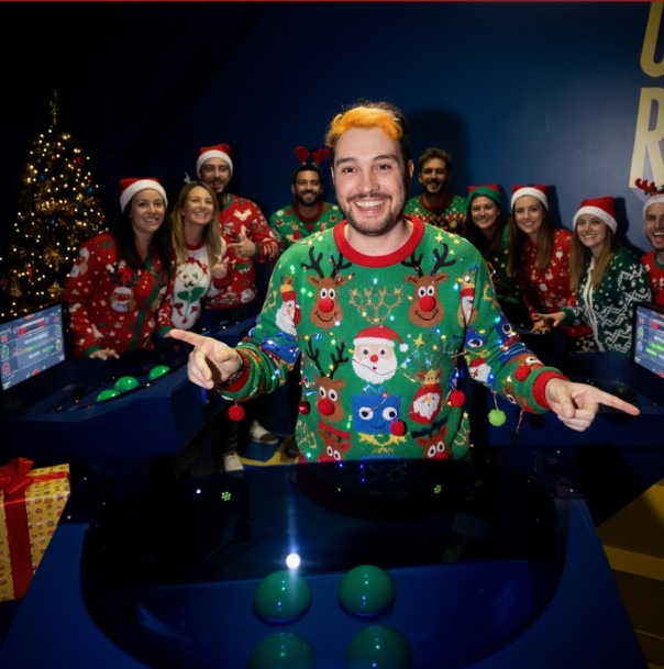 Group of friends in festive Christmas sweaters and Santa hats enjoying a holiday-themed quiz game at Quiz Room Dubai, surrounded by decorations and holiday cheer.