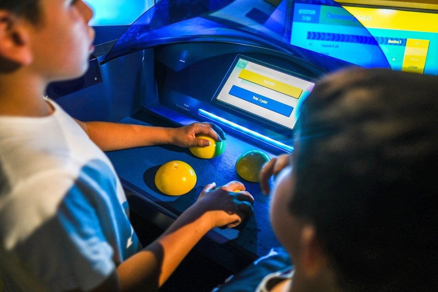 Two children playing an interactive quiz game using colorful buzzers and a touchscreen – an immersive, tech-free educational experience at Quiz Room Dubai.