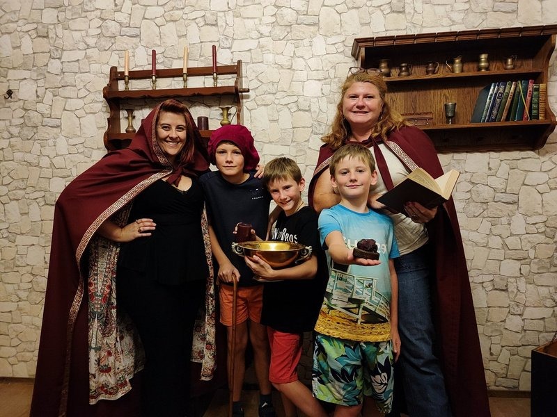 Children and adults dressed in wizard costumes inside an escape room, holding props and solving puzzles – a magical, educational team-building activity in Dubai.