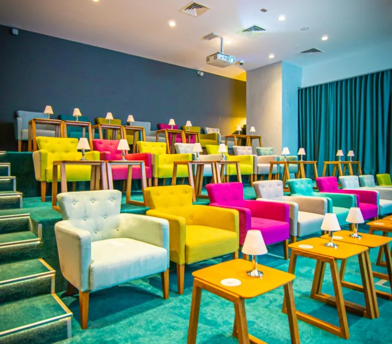 Colorful boutique cinema with plush armchairs and individual tables, designed for a cozy, private movie screening – perfect for kids’ birthday parties in Dubai.