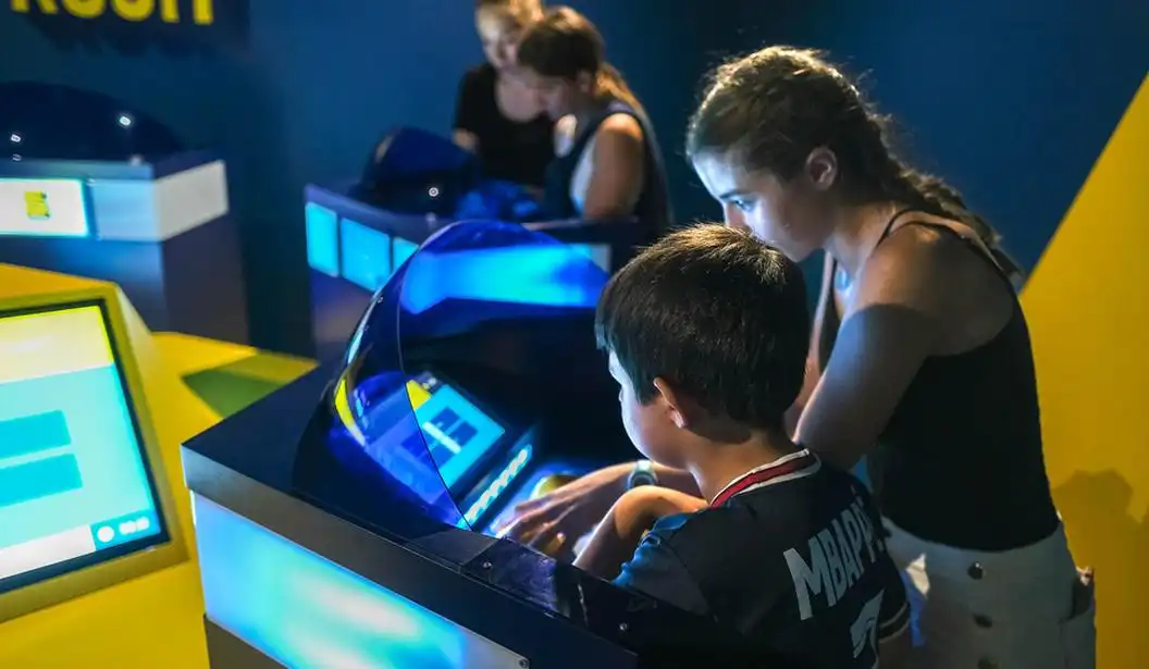 Kids and teens playing an interactive quiz game at Quiz Room Dubai, focused on screen-based challenges in a game-show-style studio.