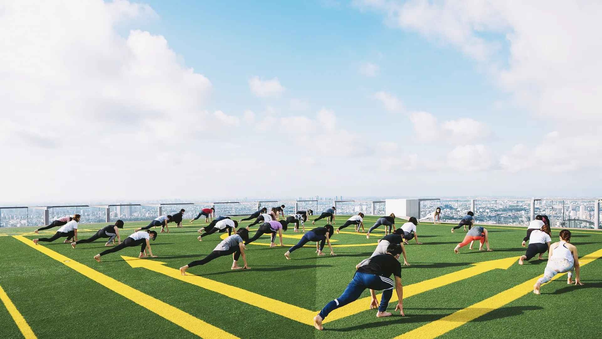 Corporate team practicing rooftop yoga with a skyline view in Dubai, ideal for mindfulness and stress-free team bonding.
