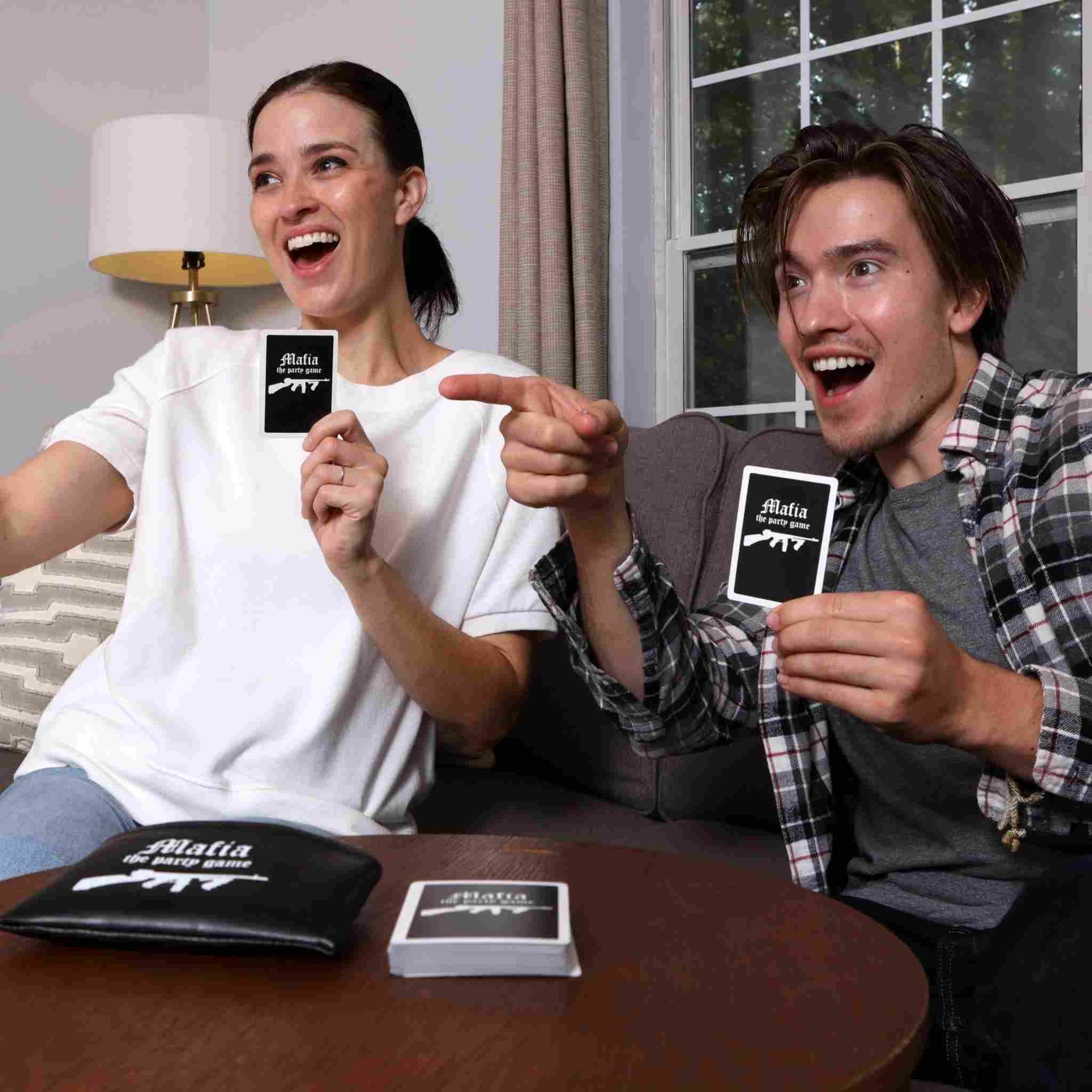 Two adults excitedly playing the Mafia party card game at home in Dubai.