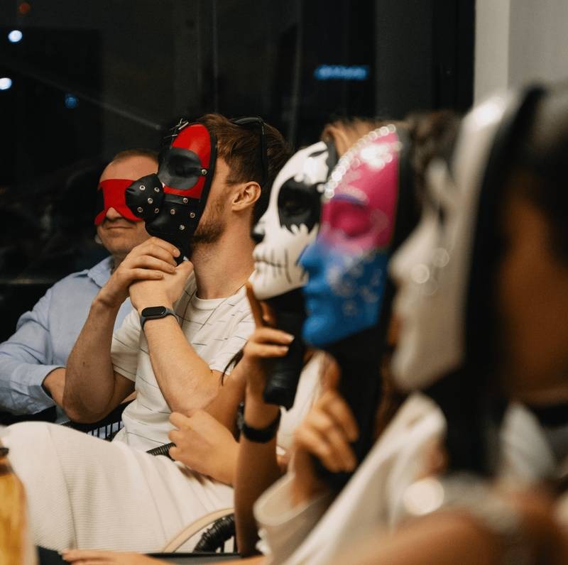 Group of friends wearing theatrical masks during a murder mystery party game in Dubai.