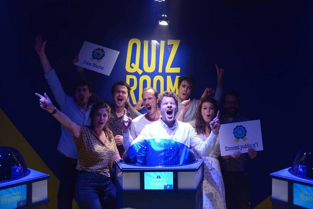 Excited group of friends competing in a buzzer-style quiz game show at Quiz Room Dubai.