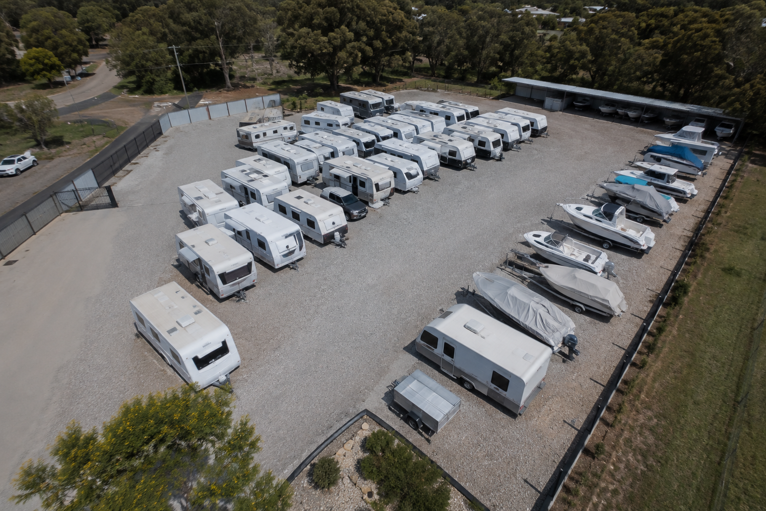 Aerial view of caravans and boats parked in marked bays at a secure outdoor storage yard.