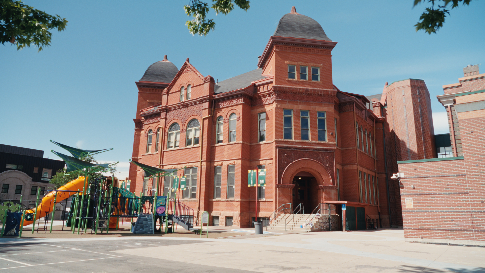 The red brick exterior of a school with a playground