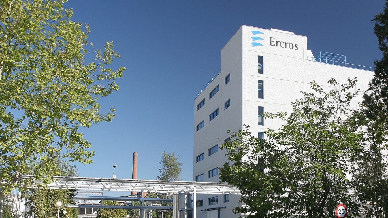 Edifício da Ercros com o logótipo no topo, rodeado de árvores.