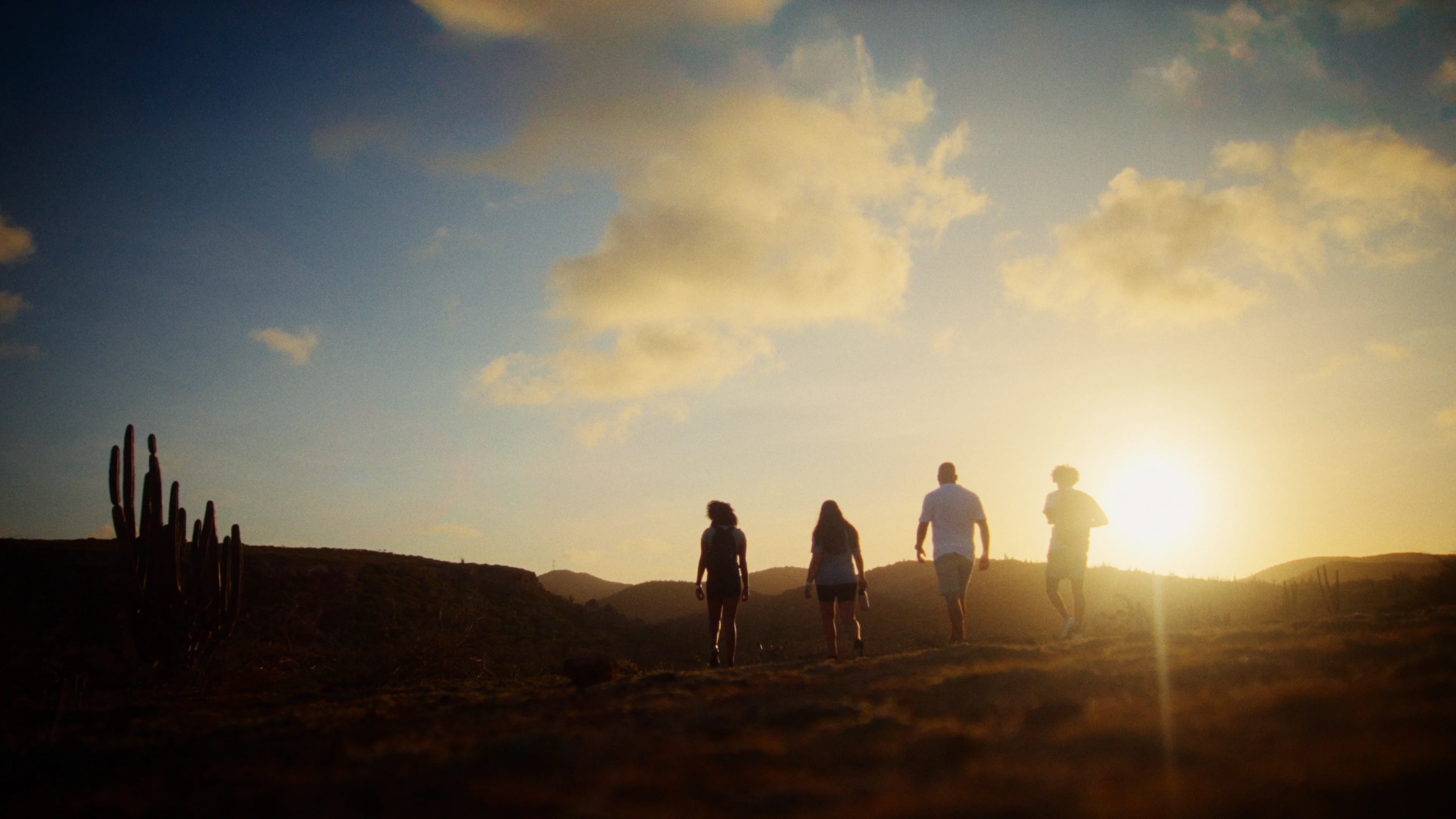 people walking in desert landscape at sunset