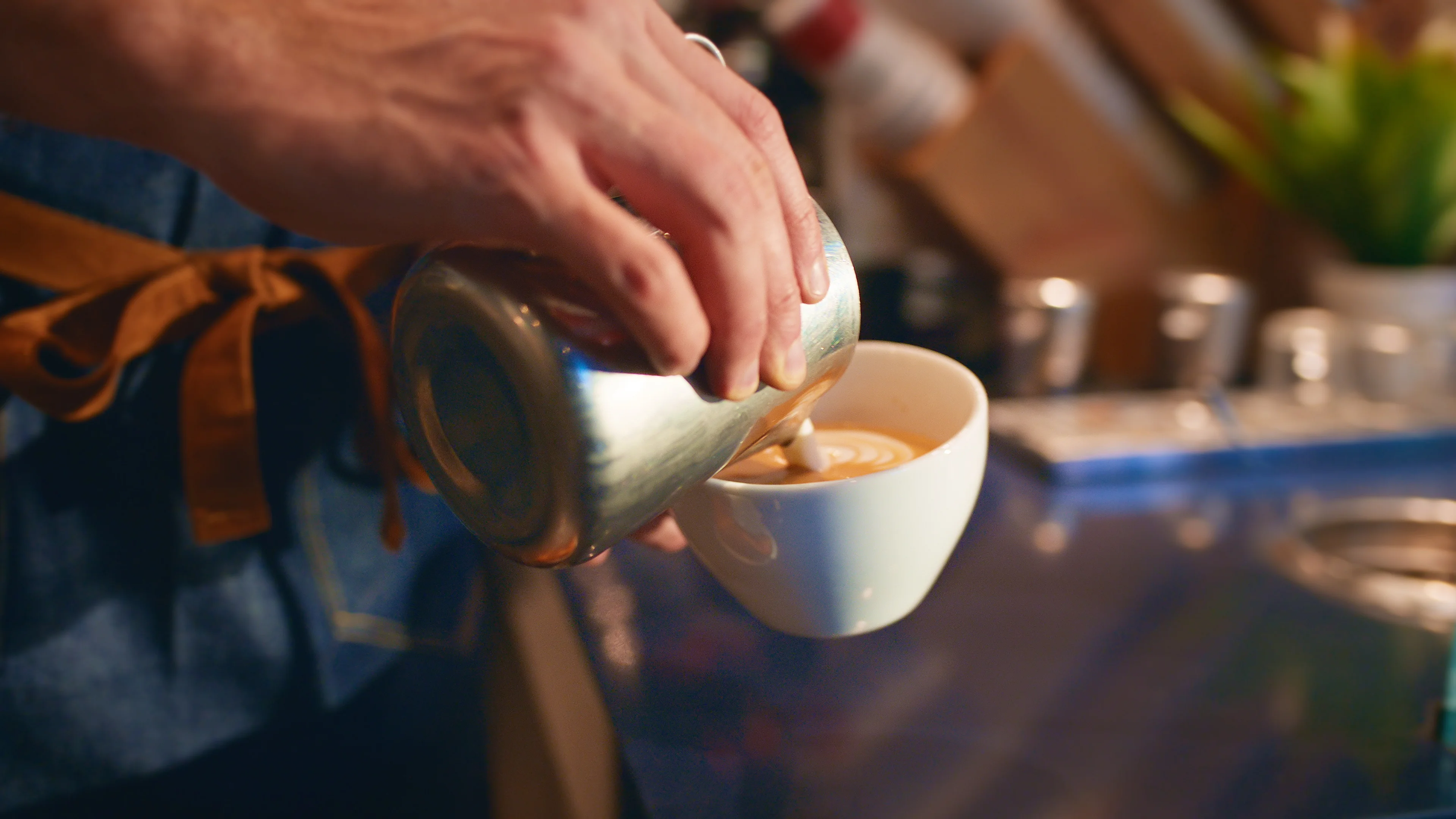 barista pouring milk into espresso making a latte