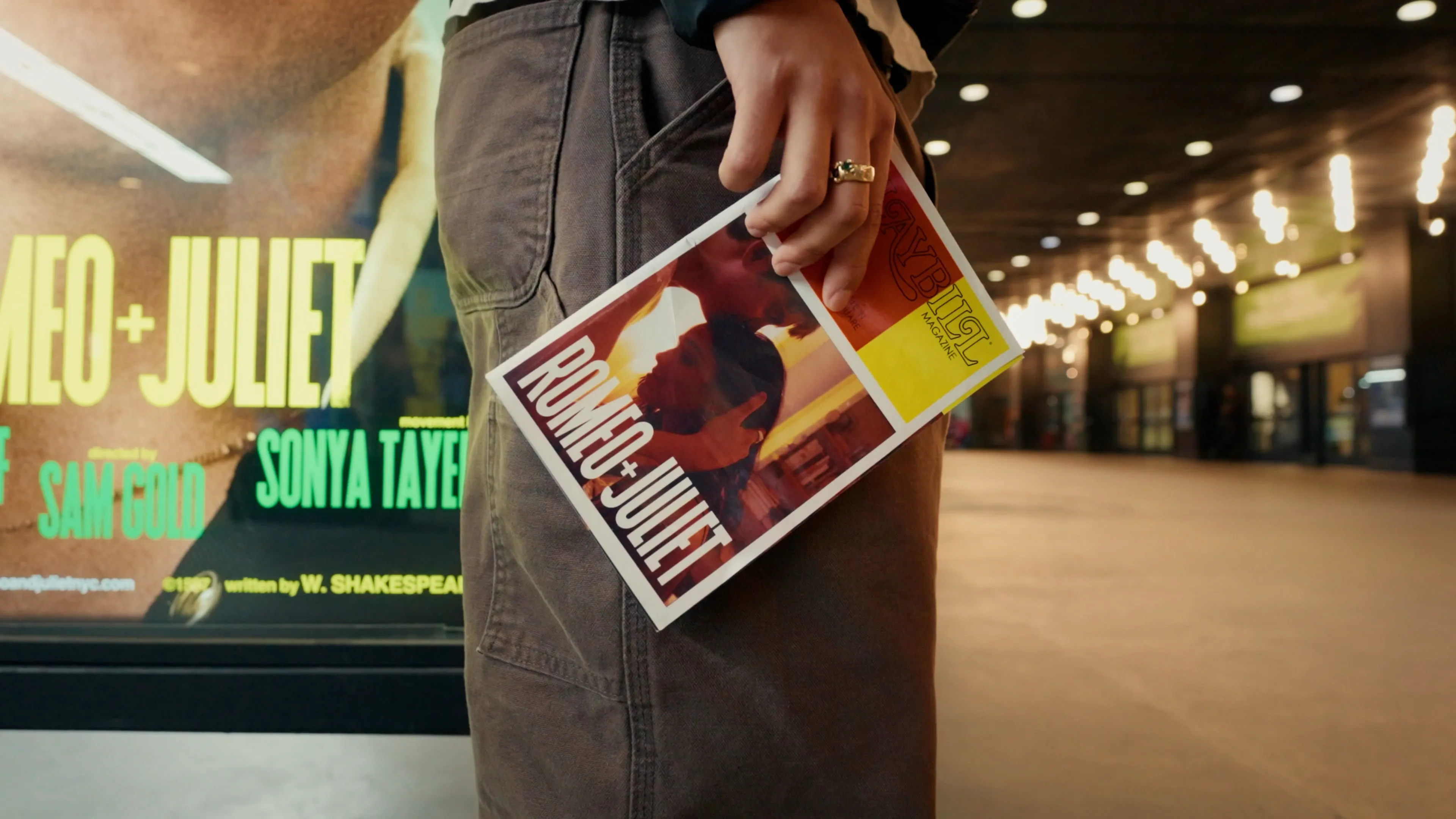person holding a playbill outside a theatre