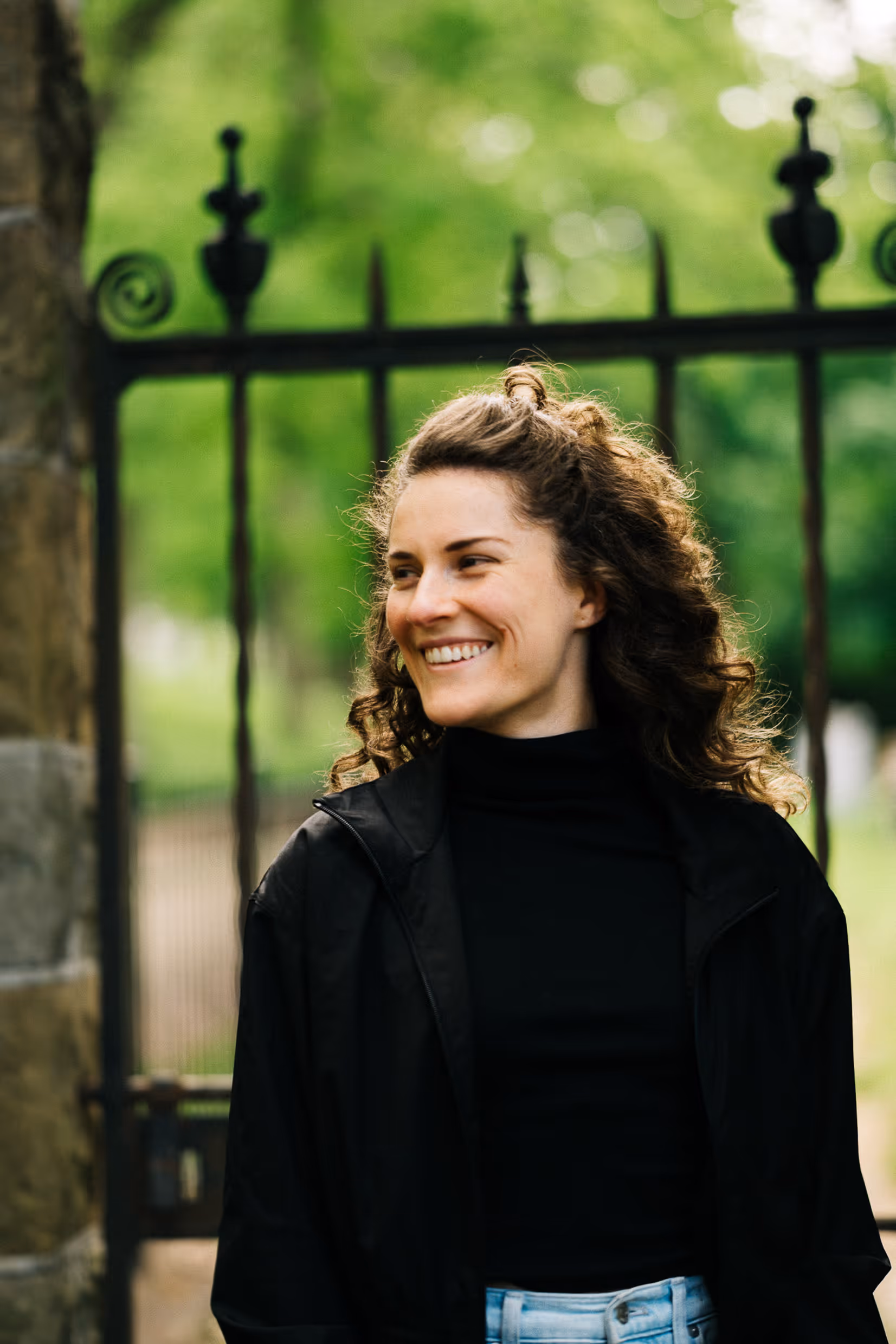a woman smiling in front of a gate