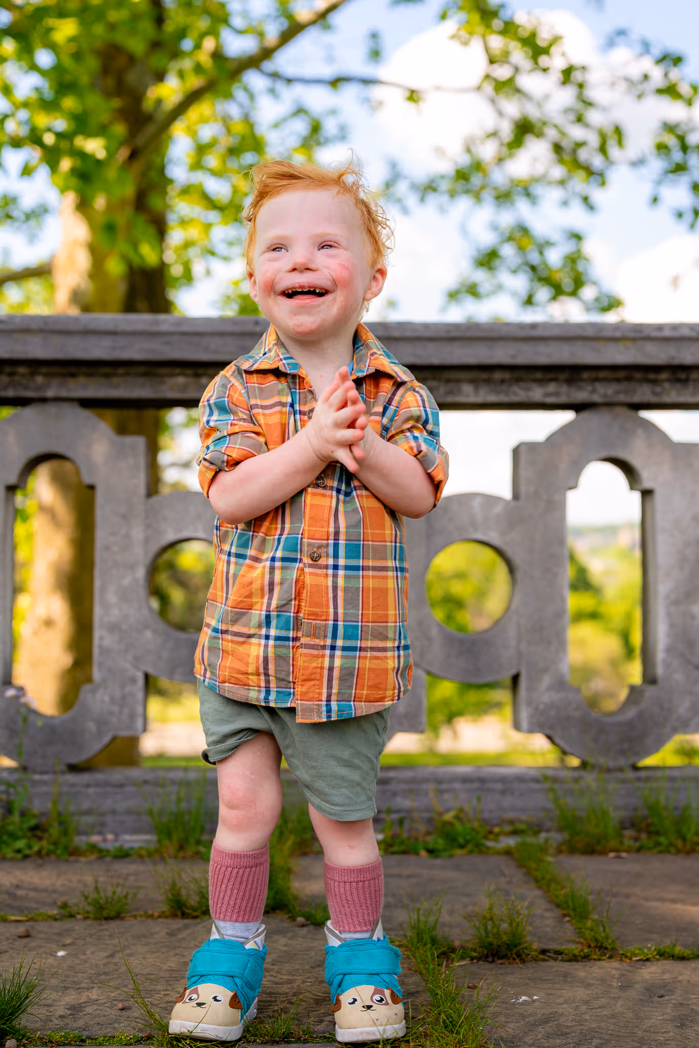 a child with red hair and a dirty face standing on a stone bridge