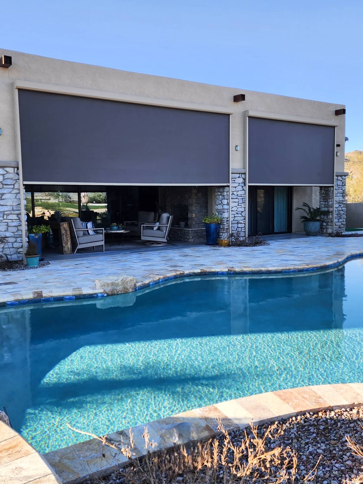 Motorized solution screens deployed over a large poolside patio on a Tucson home, providing shade and privacy while maintaining an open outdoor living space.