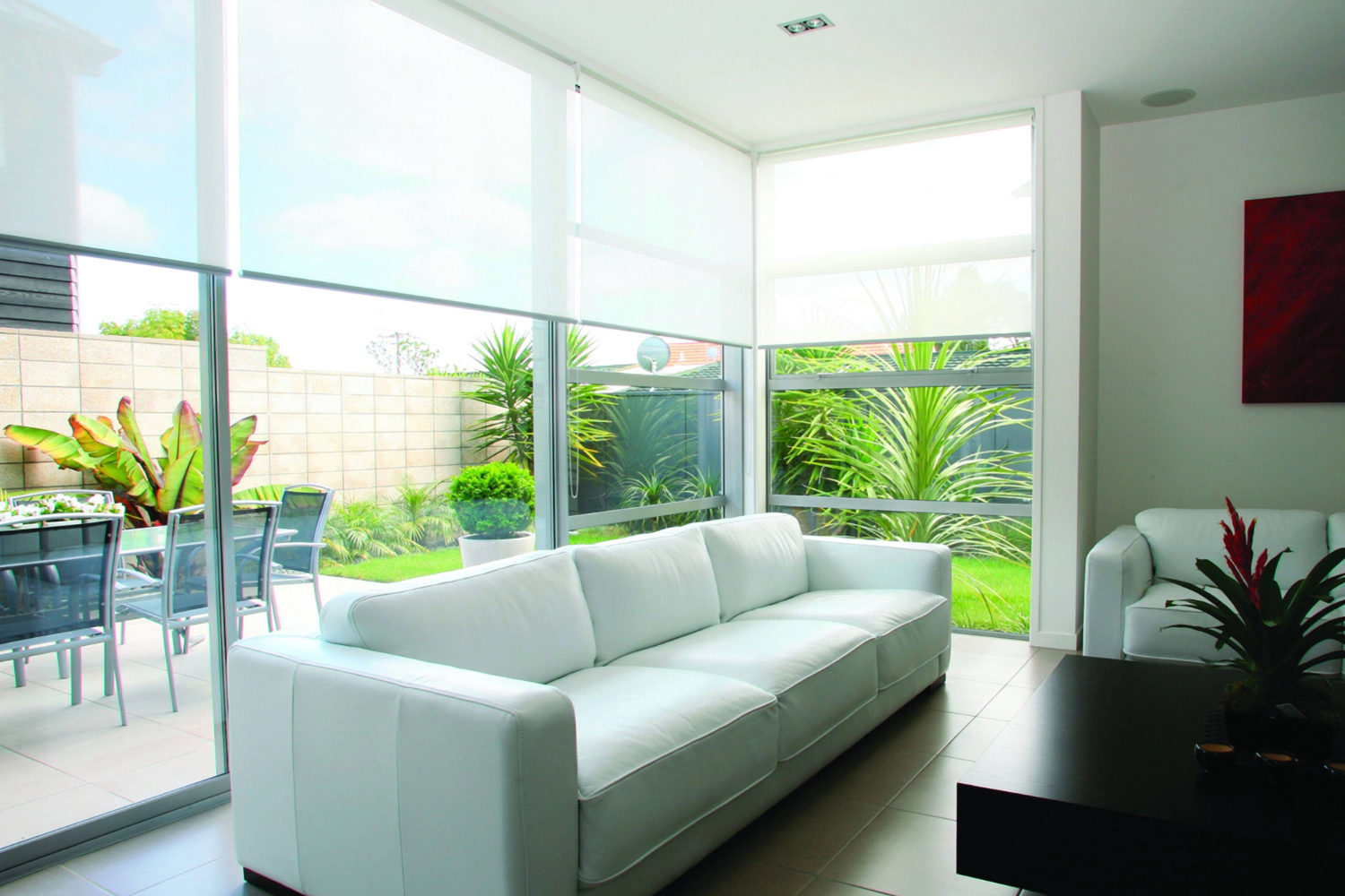 Modern living room with white sofa and large window screens.
