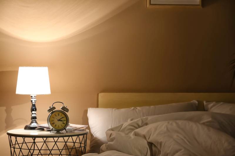 Cozy bedroom with lamp and alarm clock.