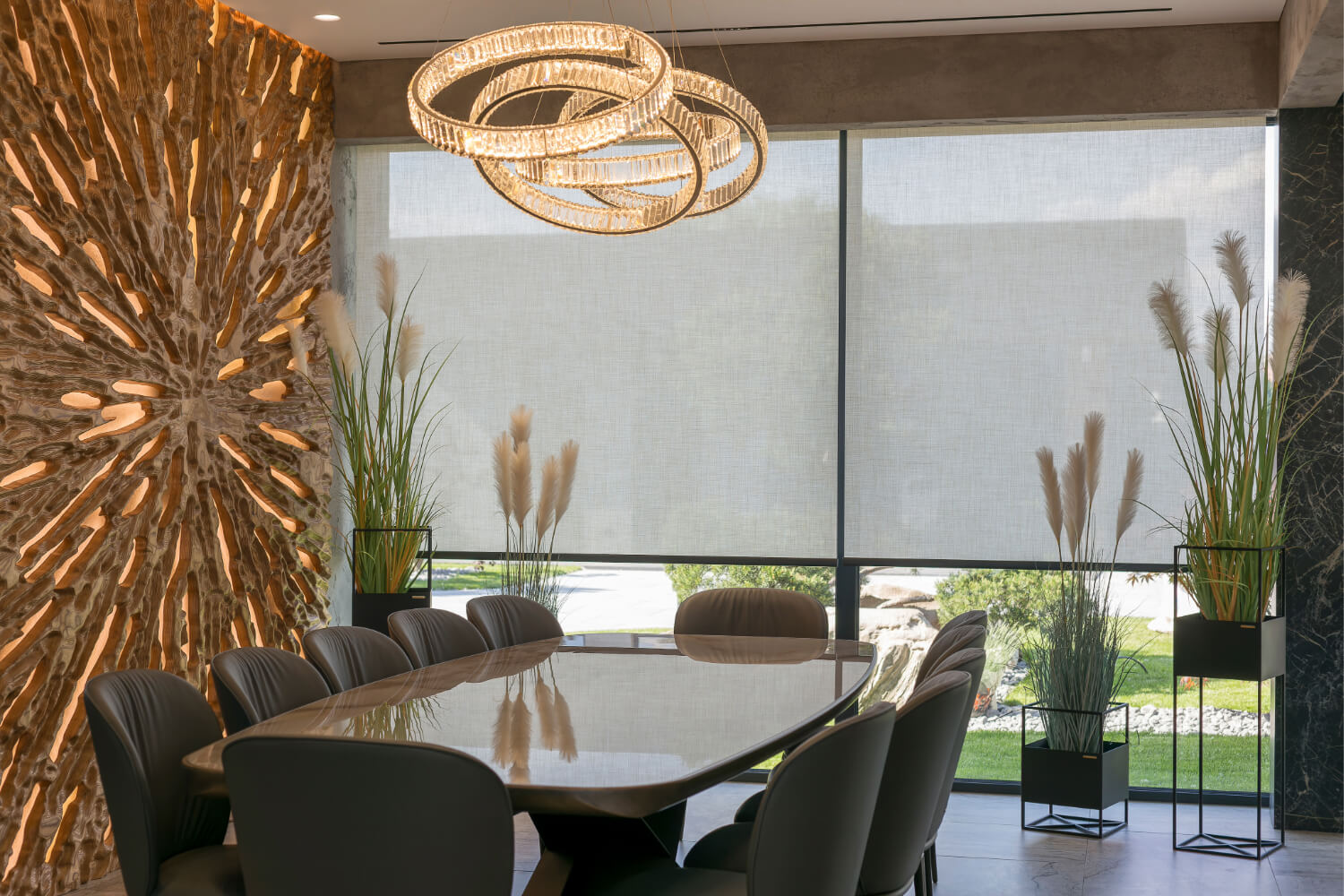 Dining room with large window, rolled-up screen, modern chandelier, and decorative wall.