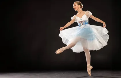 Ballerina i vit och blå klänning dansar graciöst på svart bakgrund