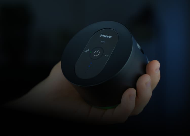 Hand holding a black cylindrical device with a power button and indicator lights labeled 'imapper'.
