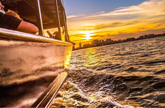 A boat traveling down a body of water at sunset.