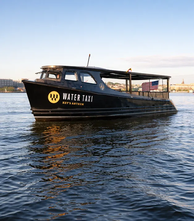 A black water taxi boat floating on top of a body of water.