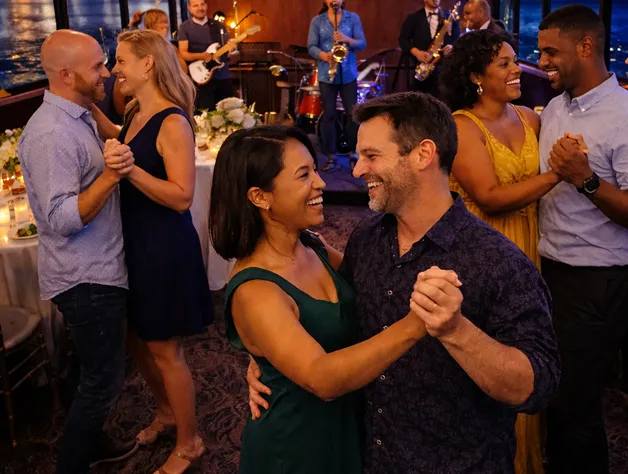 A man and woman dancing together in a room full of people.