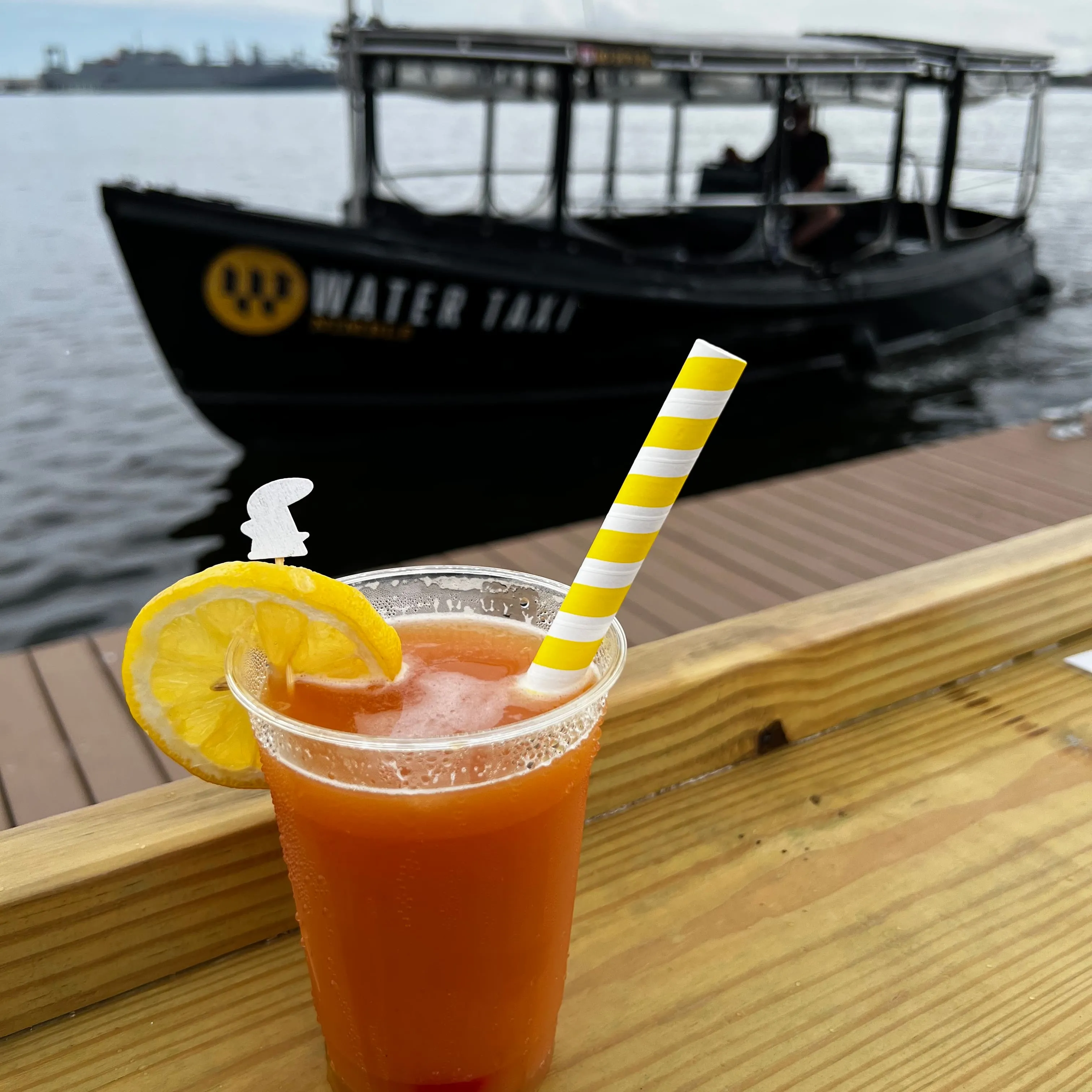 A glass of orange juice with a straw and a lemon slice.
