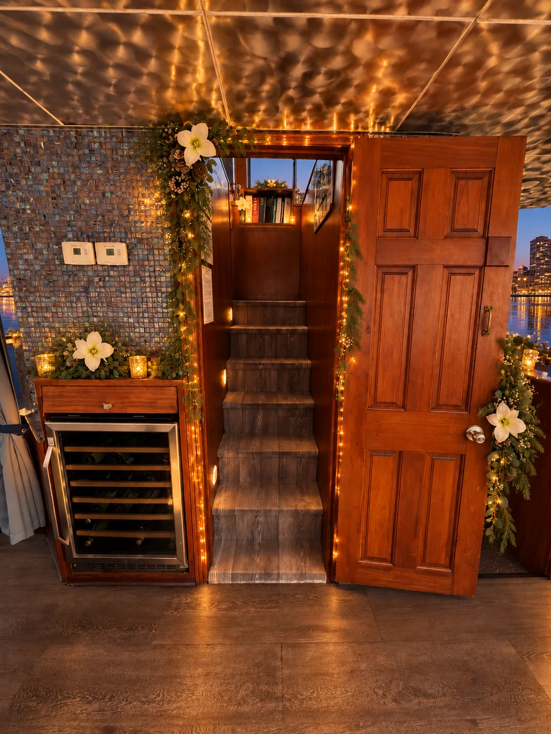 A wood-paneled staircase and wine fridge aboard Lady Thames trimmed with garland and string lights