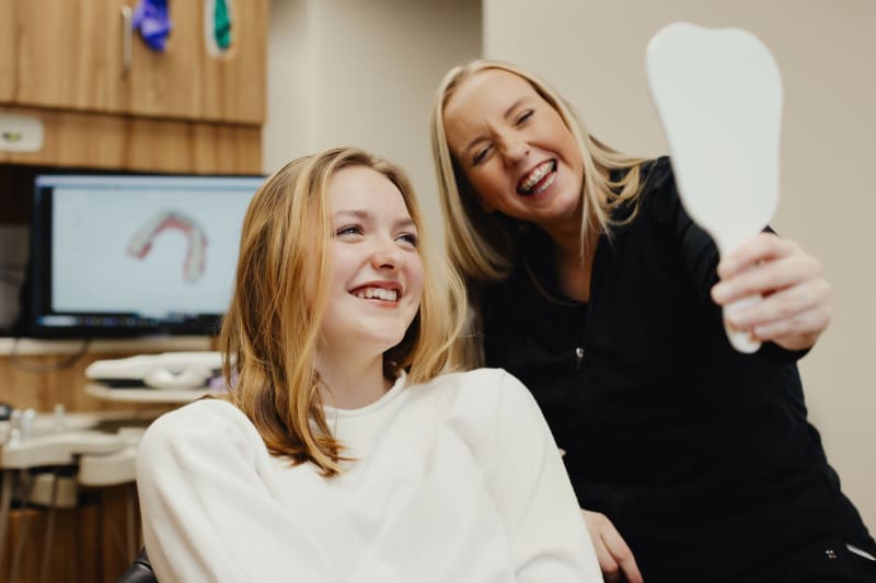 Female dentist with dark hair smiling at female patient during dental office visit