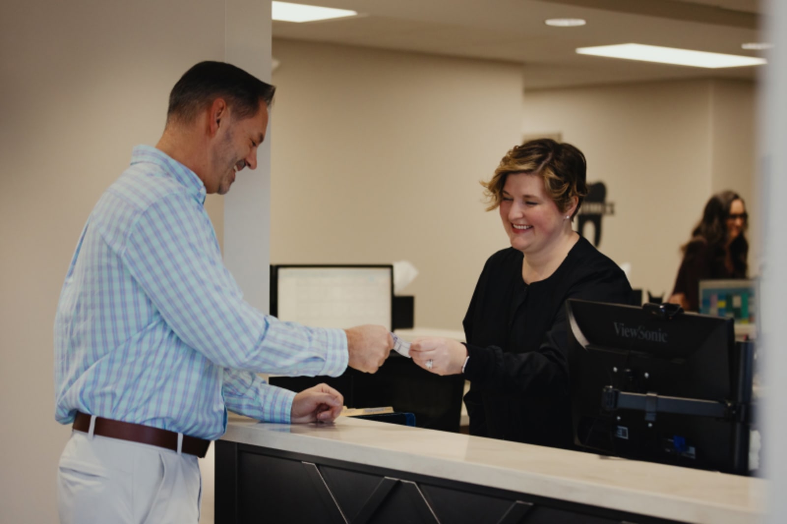 Patient receiving welcome and check-in at dental practice reception desk