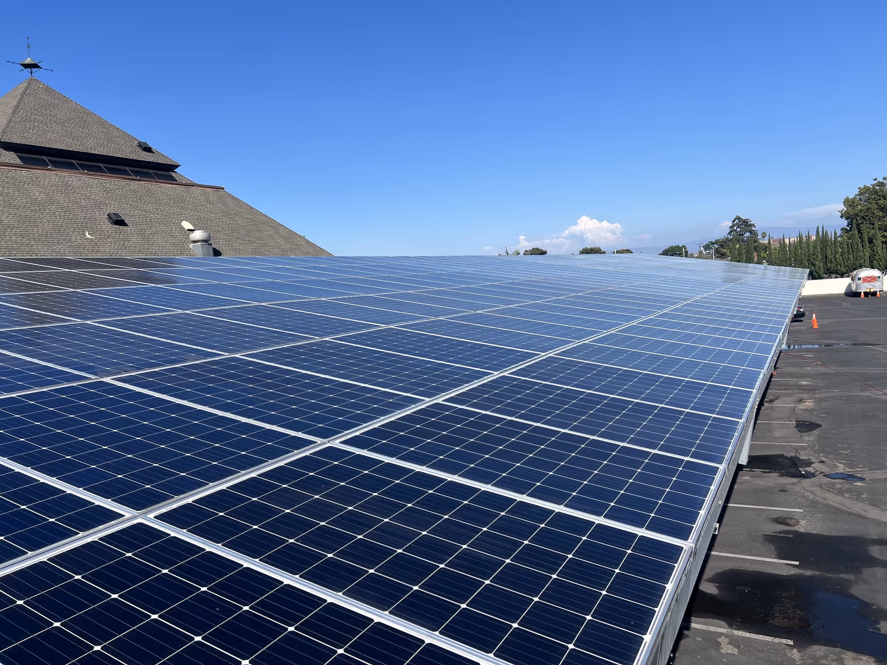 Large rooftop solar panel array under clear blue sky generating renewable energy.