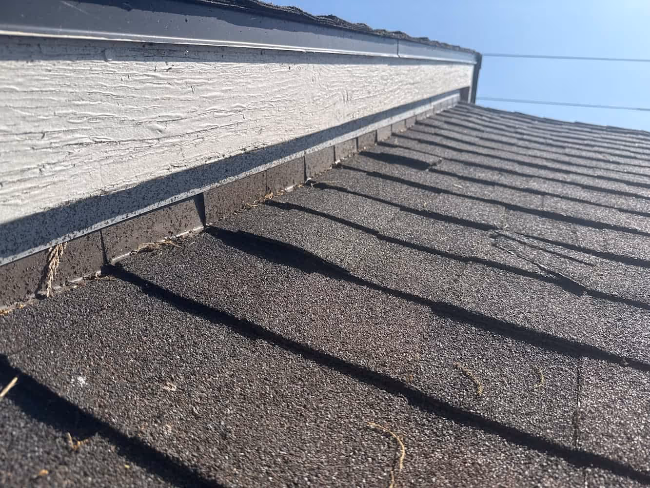 Close-up of a roof edge and shingles during a roof inspection for damage assessment