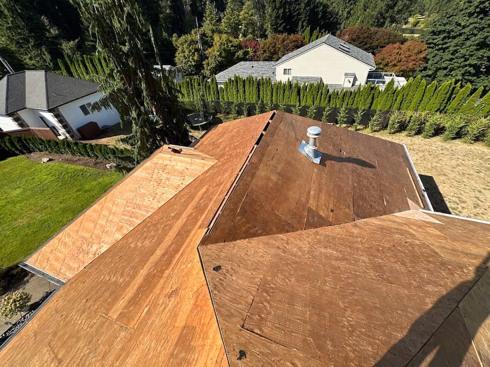 Residential roof under repair with exposed wooden decking during leak repair work.