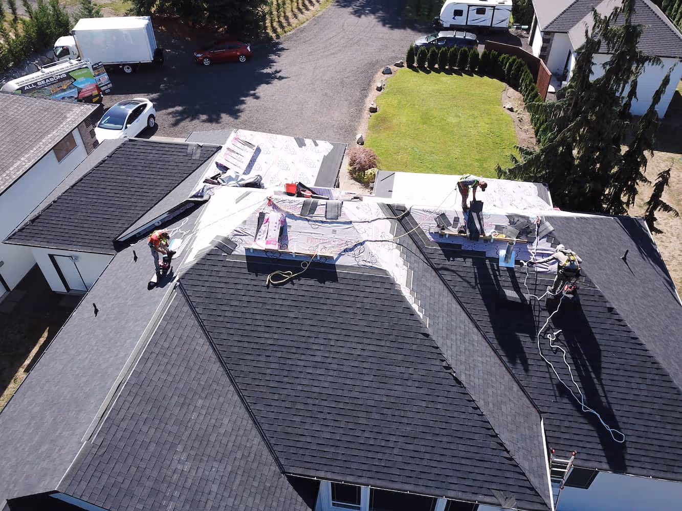 Roofing crew installing new asphalt shingles on a residential home during a shingle roof installation service.