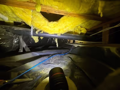 Crawl space pipe with insulation hanging and no insulation around the pipe itself.