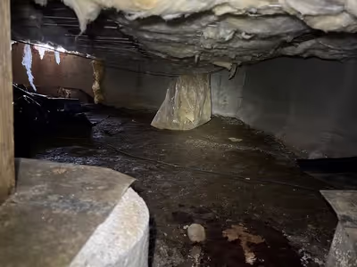 crawl space with missing vapor barrier and hanging insulation