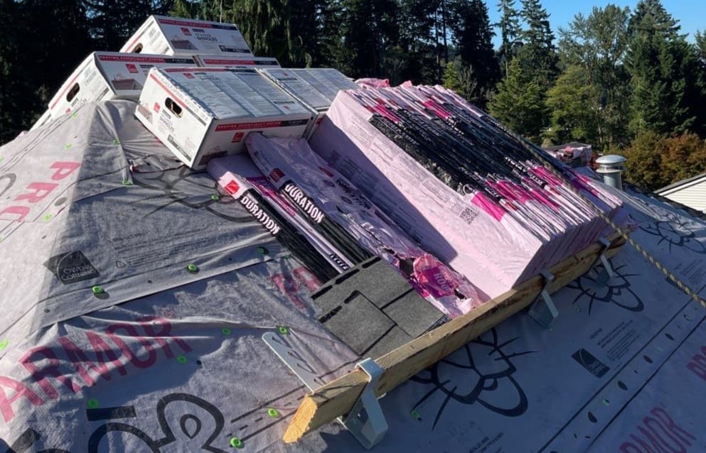 shingle bundles sitting on the roof supported by a plank