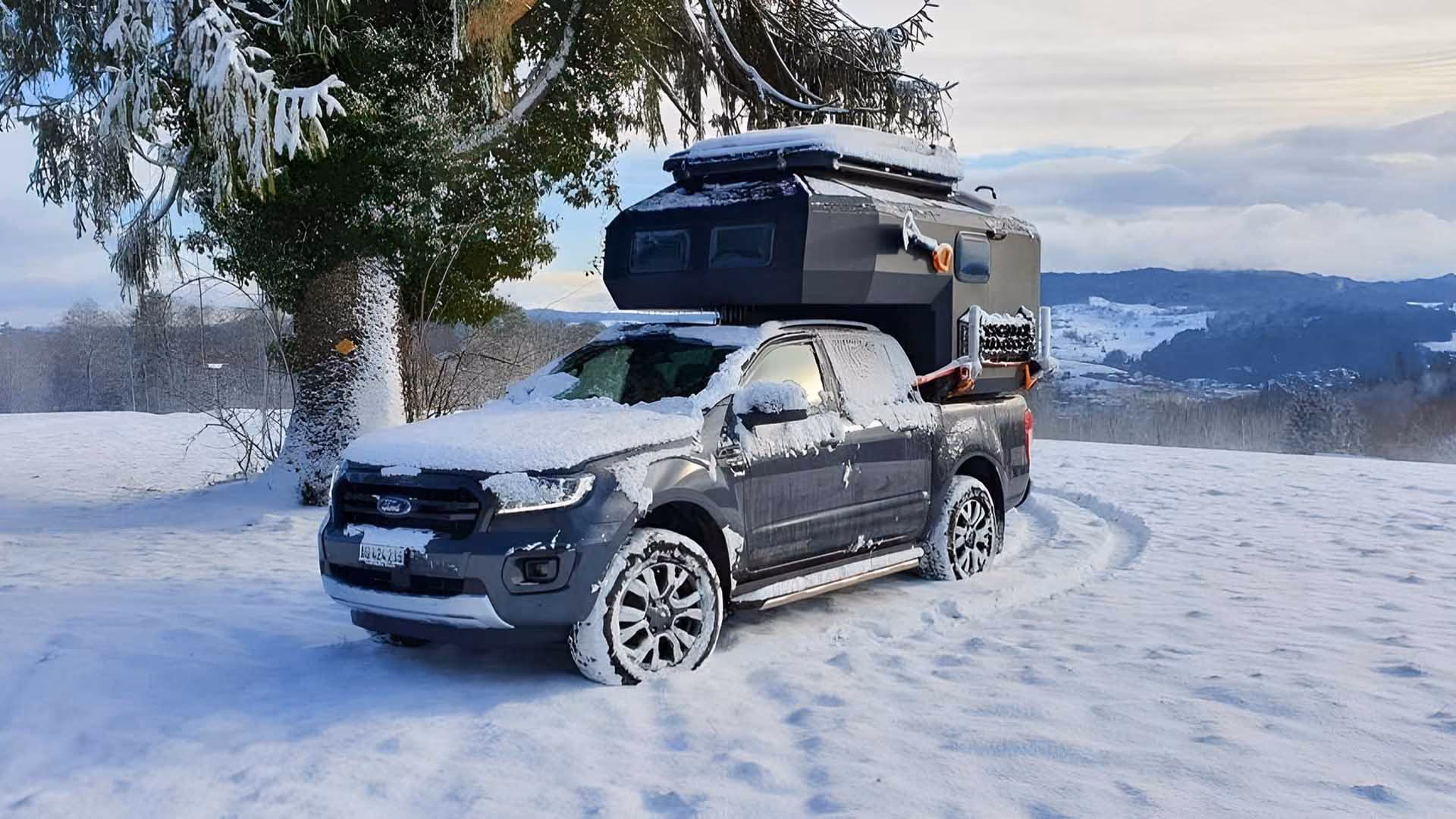 Uozi camper on a black pickup in a snowy landscape