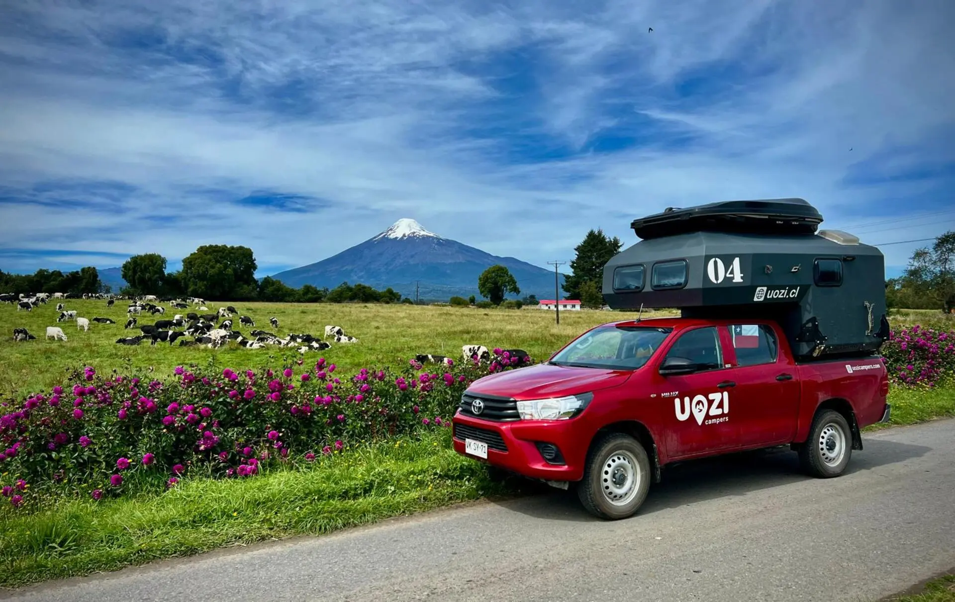 Uozi camper on a rural road with a snow-capped volcano in the background