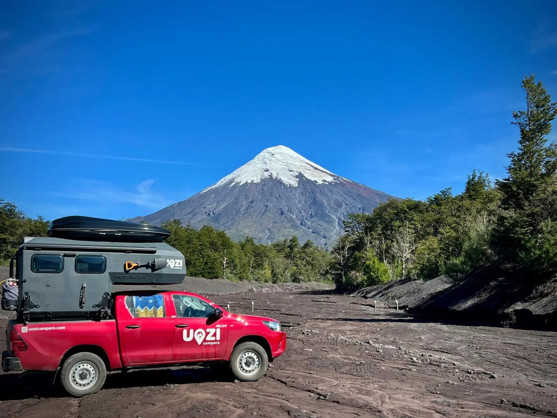 Red pickup with Uozi camper in front of Osorno volcano