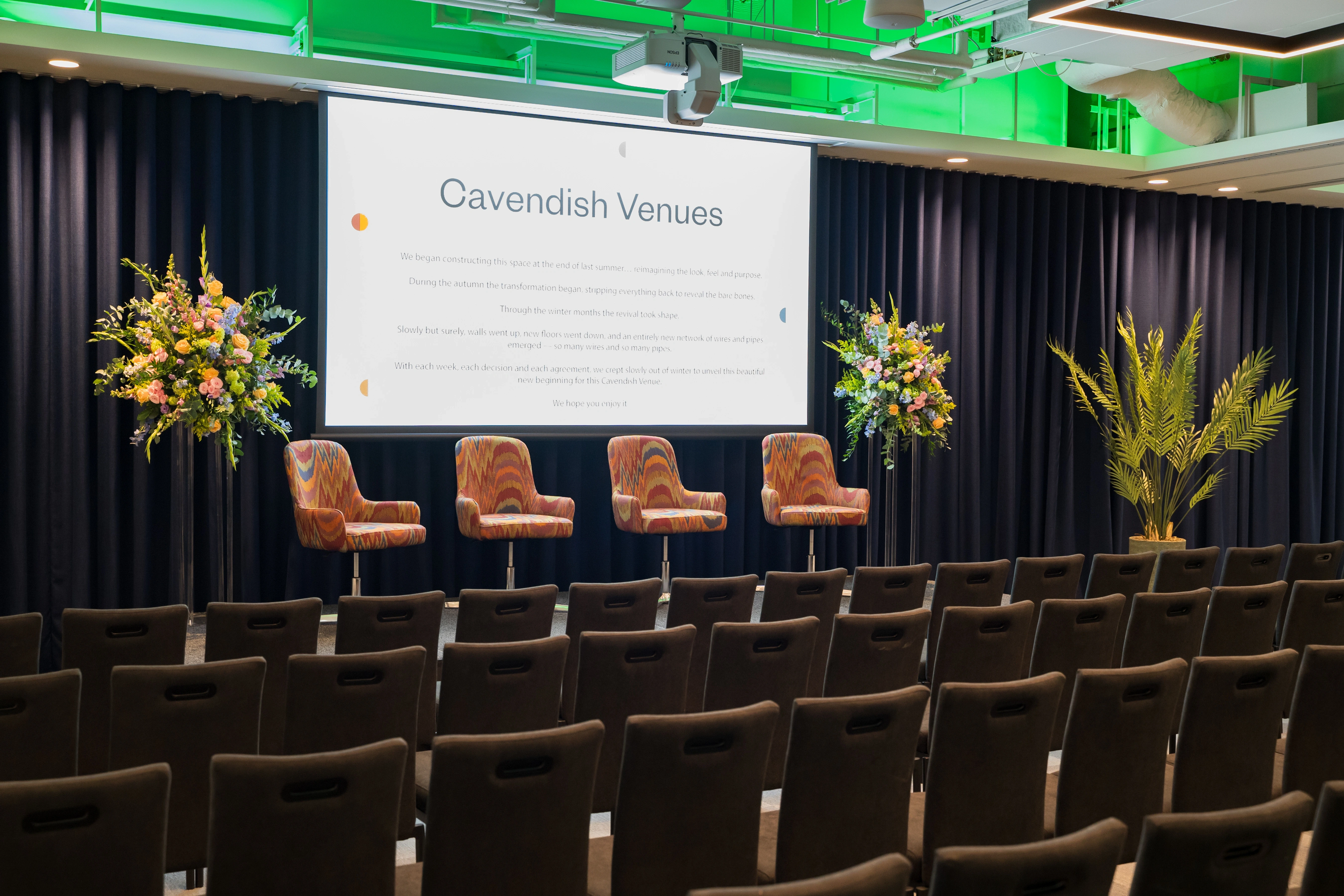 A panel stage set with four chairs and floral displays in the auditorium at 1 Basinghall Avenue