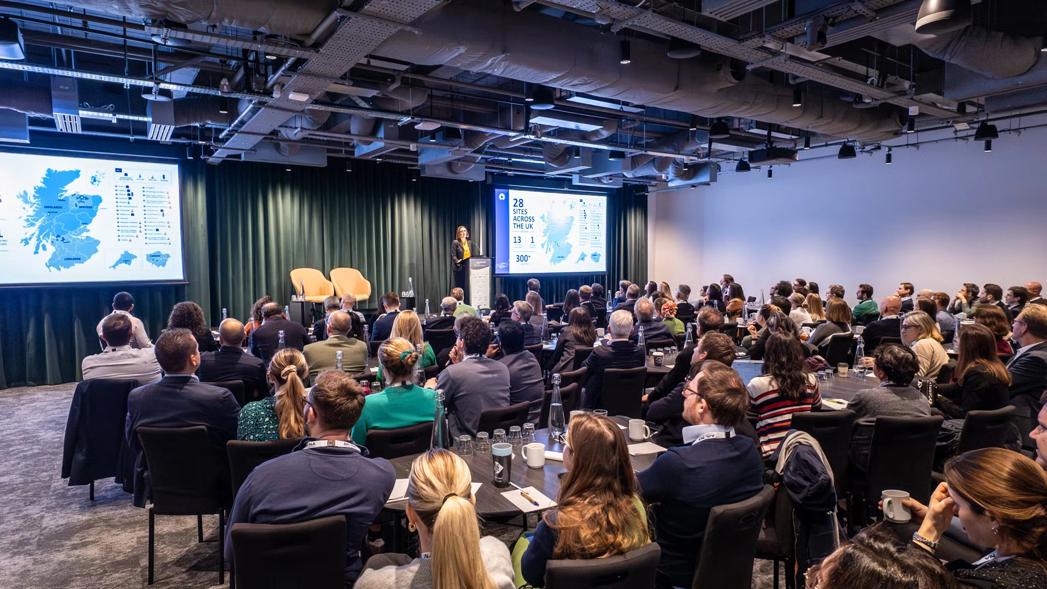 Delegates seated in a half-moon layout facing the screens at The Minster Building