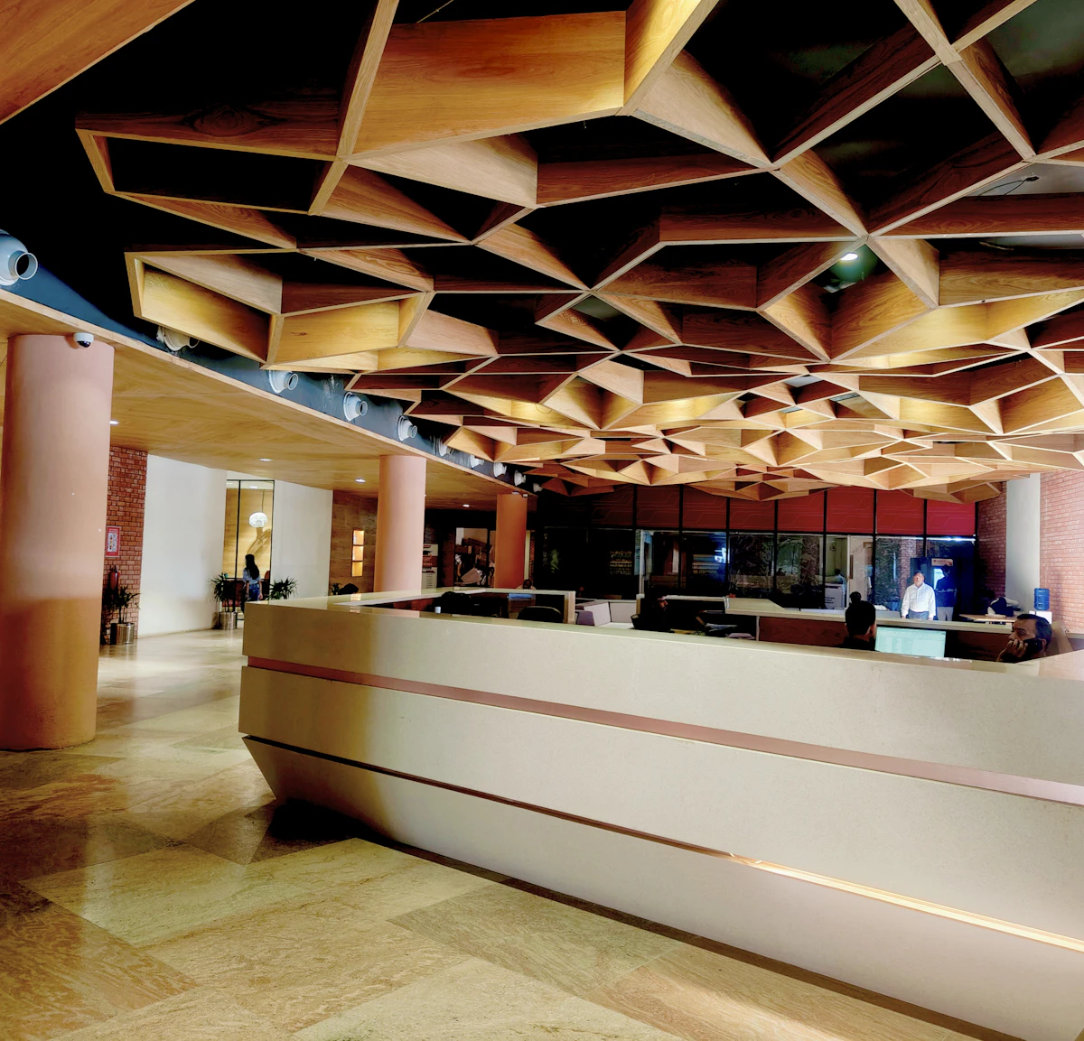 Modern office reception desk in a lobby with a geometric wooden ceiling