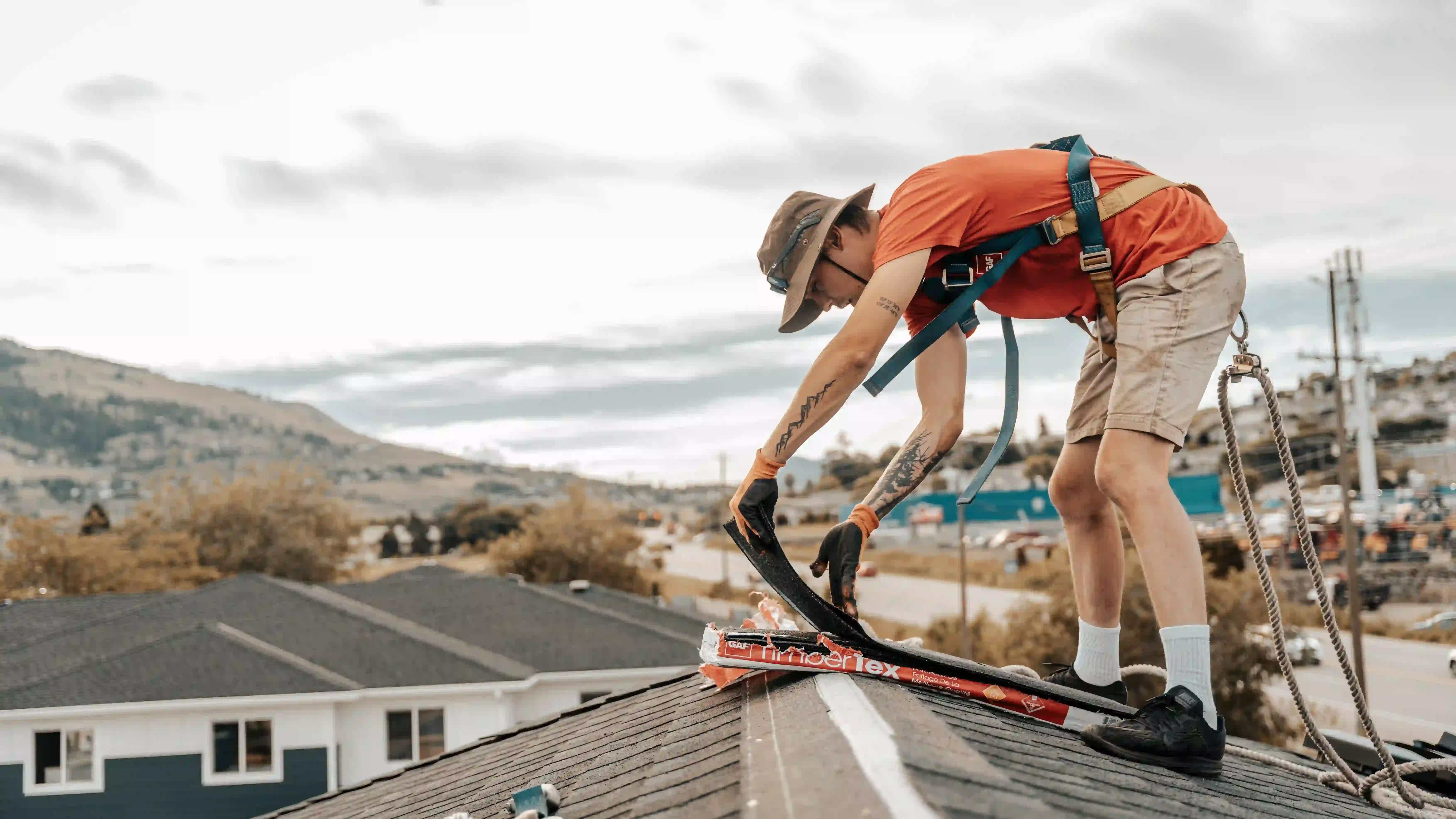 roofer laying down roofing tile on home